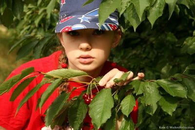 Cute solo girl Kate keeps her ball cap on while undressing among the trees