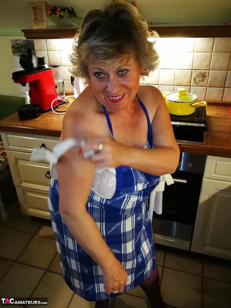 oud huisvrouw Caro neemt uit haar ondergoed in keuken schort en kousen