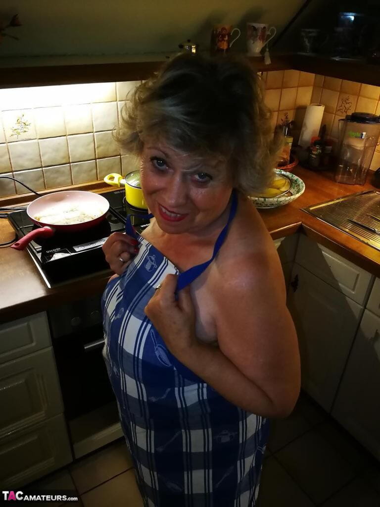 alt Hausfrau Caro Nimmt aus Ihr Unterwäsche in Küche Schürze und Strümpfe