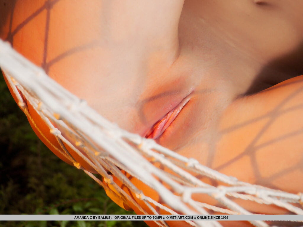Teen glamour model Amanda C posing naked on hammock next to the ocean
