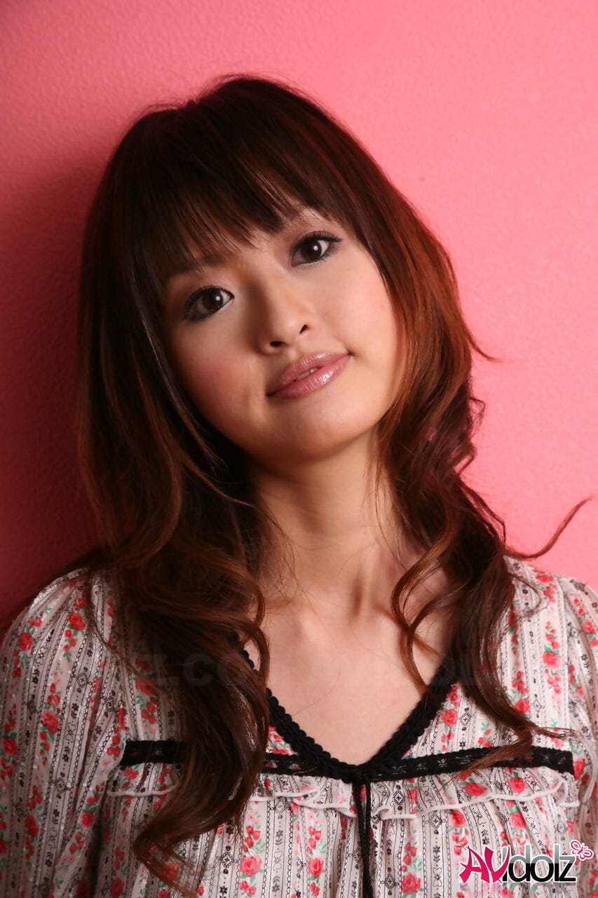 जापानी मॉडल के साथ एक सुंदर चेहरा खड़ा है कपड़े के साथ के खिलाफ एक गुलाबी दीवार