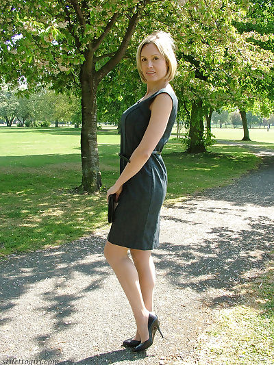 Clothed business woman shows off her sexy legs in high heels in the park